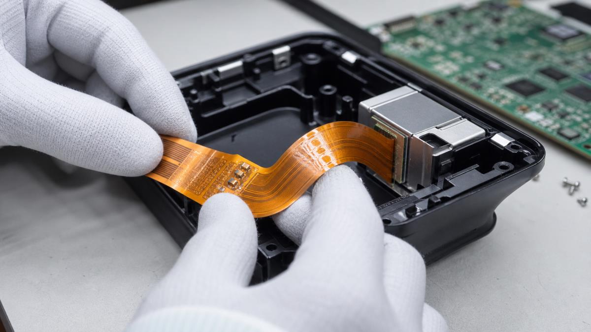 Flexible PCB bending through an electronics enclosure with reinforced connector ends