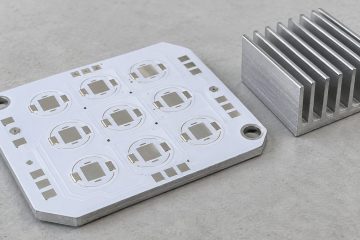 White aluminum-backed PCB prototype beside a separate metal heat sink