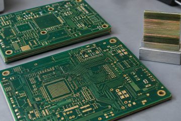 Bare multilayer circuit boards and a laminate cross-section sample on a laboratory bench