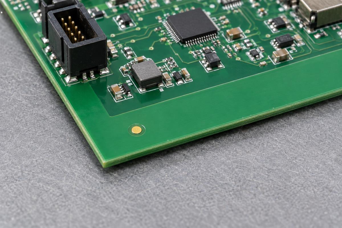 Copper fiducial and clear board edge beside assembled components, AI-generated illustration