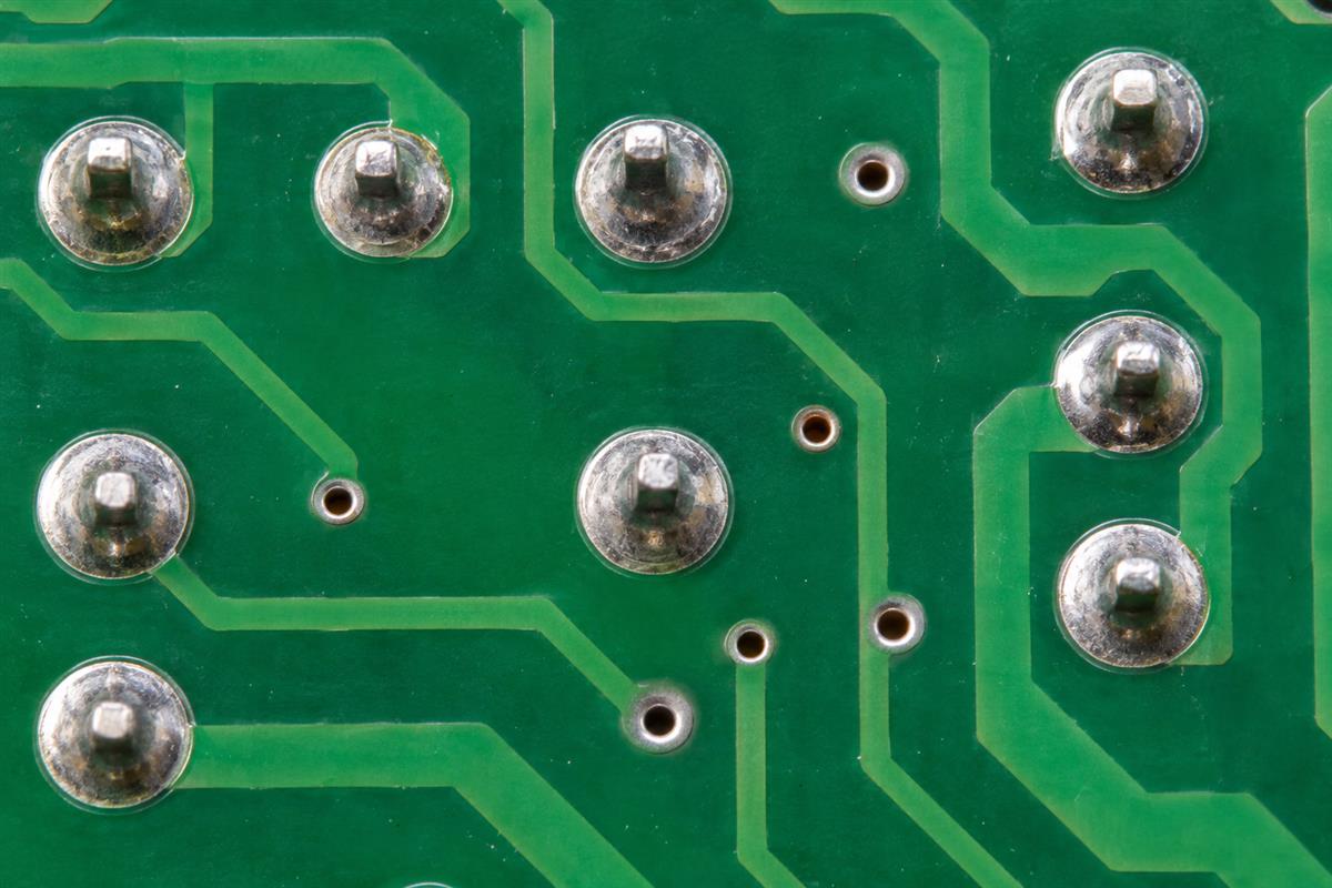 Illustrative close view of through-hole solder joints, circular pads and smaller vias