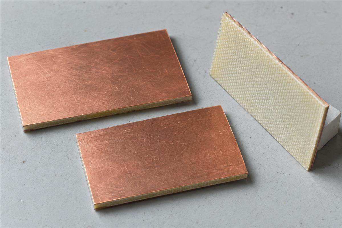 Copper-clad laminate coupons showing copper faces and a bare insulating back, AI illustration