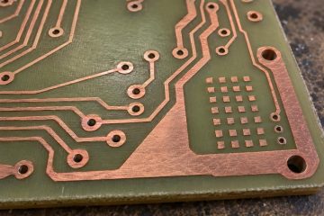 Illustrative bare PCB with isolated copper thieving squares beside functional traces