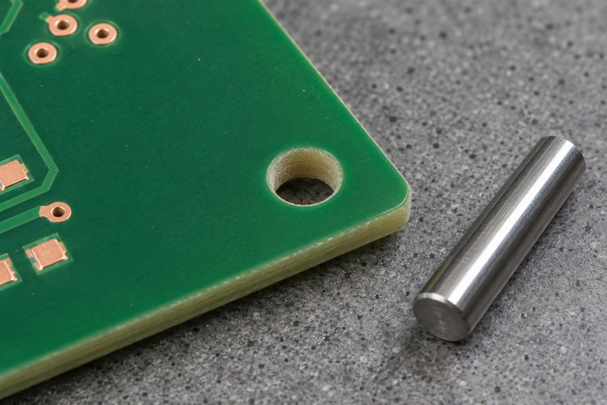 Illustrative smooth gauge pin beside a non-plated PCB tooling hole