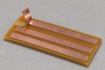 Copper-clad laminate coupon with a narrow copper strip lifted from its surface