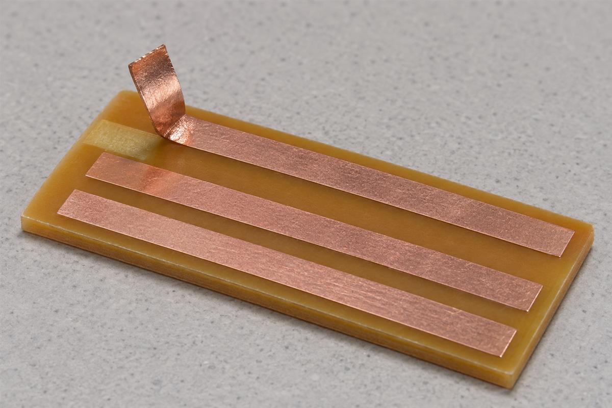Copper-clad laminate coupon with a narrow copper strip lifted from its surface